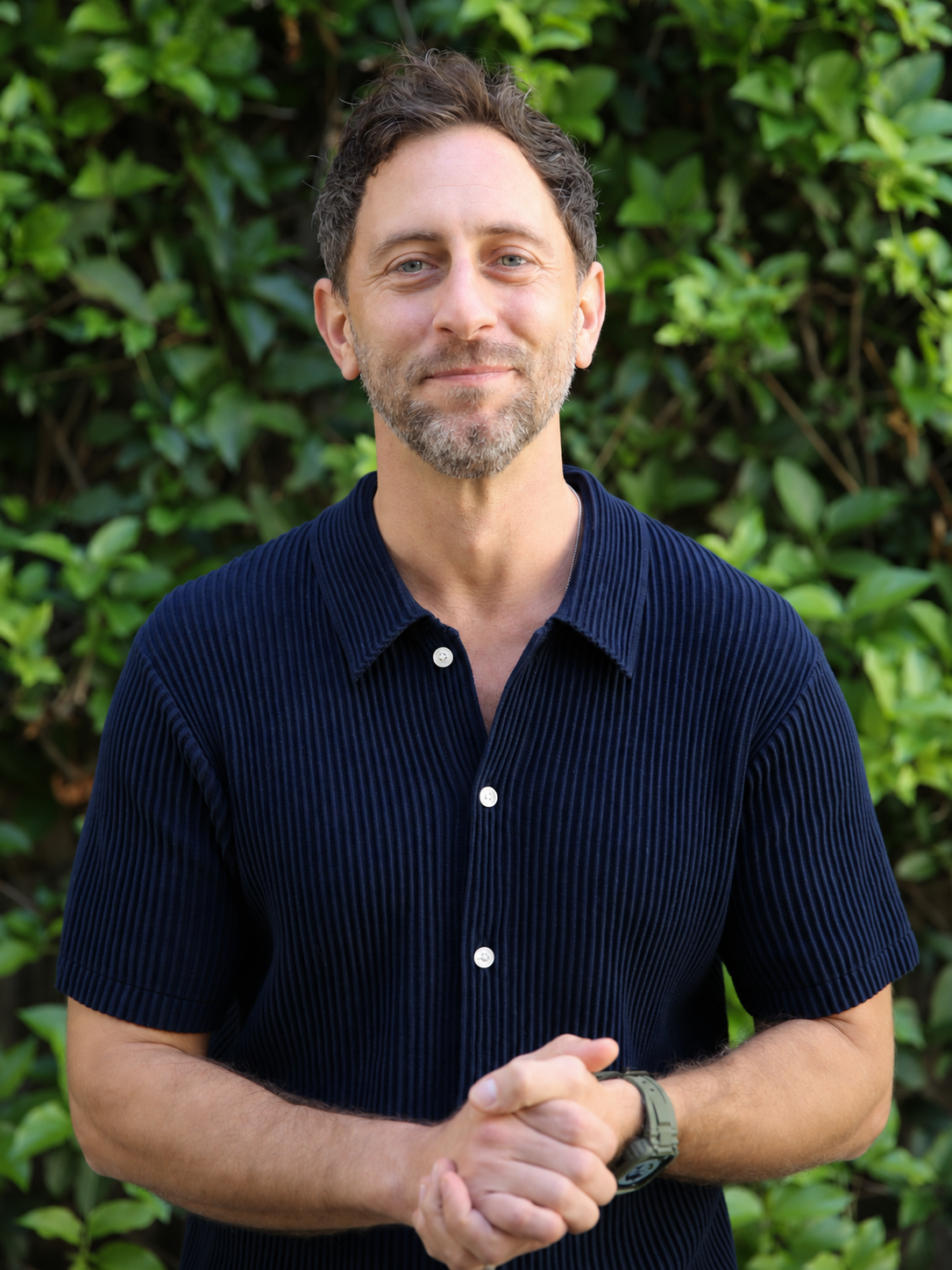 Jeremy Falk standing in front of greenery